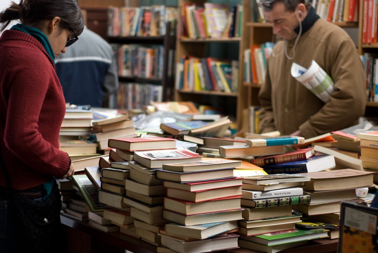 services-04 People browsing a large selection of books at a bookstore or market.